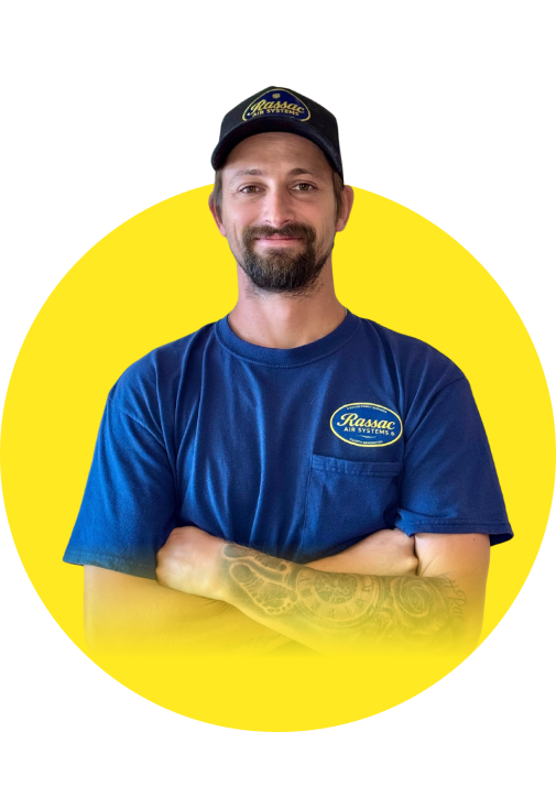 Smiling man with beard, dressed in blue work uniform with air conditioning company logo, posing with arms crossed on yellowish background, representing professionalism and confidence.